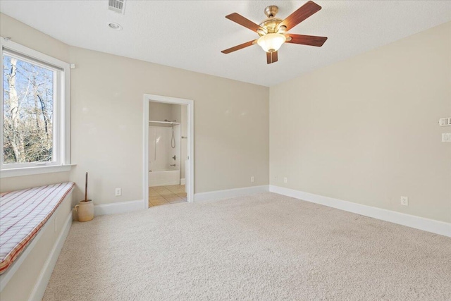 unfurnished bedroom featuring ceiling fan, light colored carpet, and connected bathroom