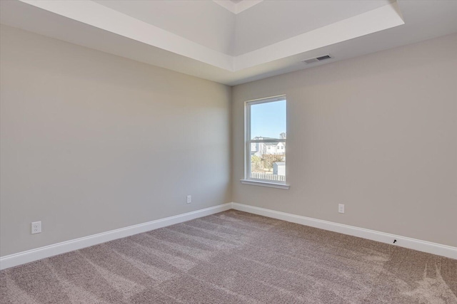 carpeted spare room with a tray ceiling