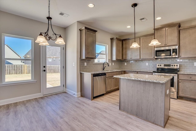 kitchen featuring a center island, an inviting chandelier, hanging light fixtures, light hardwood / wood-style flooring, and appliances with stainless steel finishes