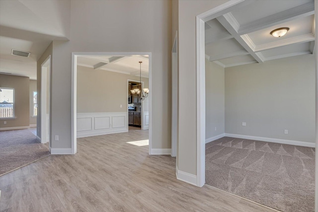 interior space featuring crown molding, beamed ceiling, a chandelier, and coffered ceiling