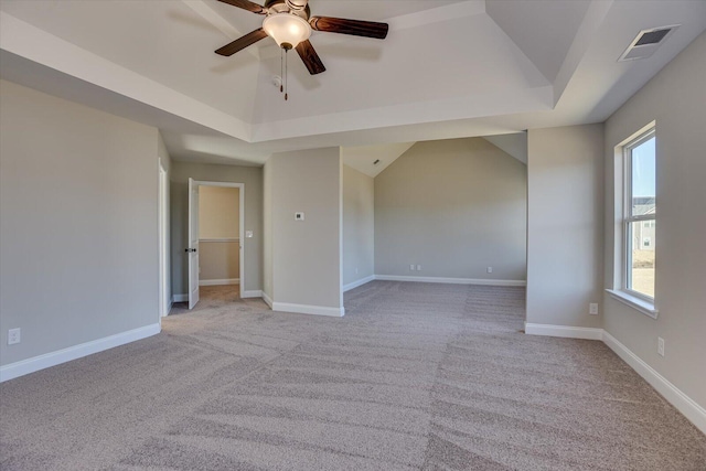 unfurnished room with a tray ceiling, ceiling fan, plenty of natural light, and light carpet