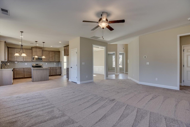 unfurnished living room featuring ceiling fan, sink, and light carpet