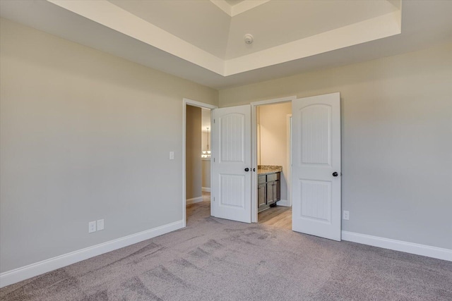 unfurnished bedroom with a tray ceiling and light colored carpet