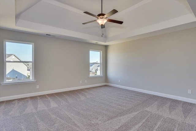 unfurnished room featuring a tray ceiling, ceiling fan, and carpet