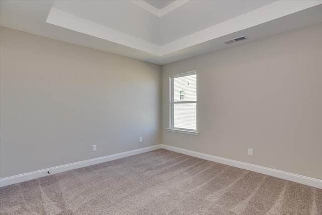 carpeted empty room featuring a tray ceiling