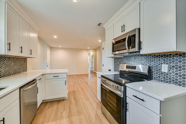 kitchen with visible vents, light countertops, appliances with stainless steel finishes, light wood-type flooring, and backsplash