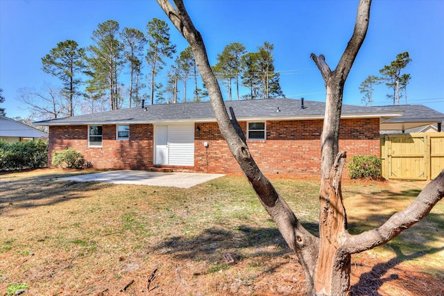 back of house featuring brick siding, a yard, a gate, a patio area, and fence