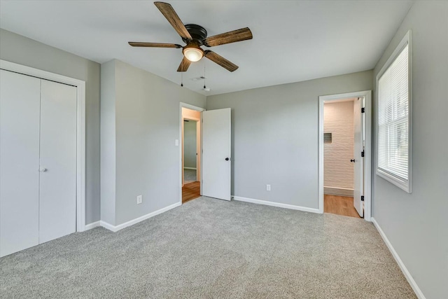 unfurnished bedroom featuring baseboards, a ceiling fan, ensuite bath, carpet, and a closet