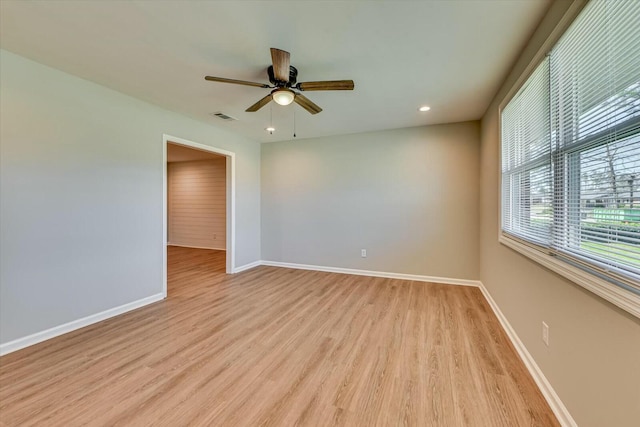 spare room featuring ceiling fan, light wood-style floors, visible vents, and baseboards