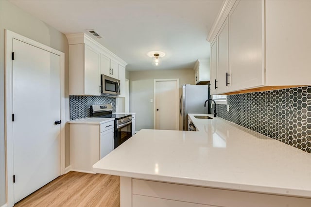 kitchen with light wood-style flooring, visible vents, white cabinets, appliances with stainless steel finishes, and decorative backsplash