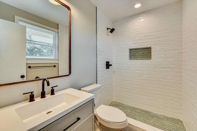 full bathroom with toilet, tiled shower, and vanity