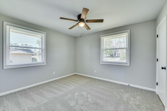 carpeted empty room with a healthy amount of sunlight, ceiling fan, and baseboards