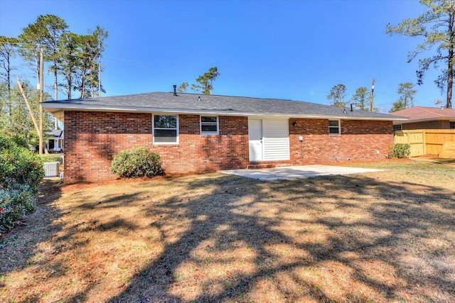 back of property with a yard, a patio area, brick siding, and fence