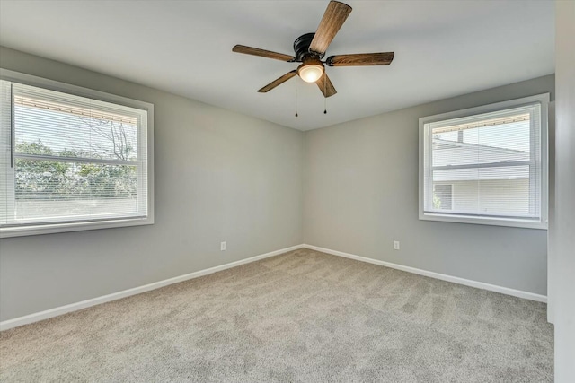 carpeted empty room with a ceiling fan and baseboards