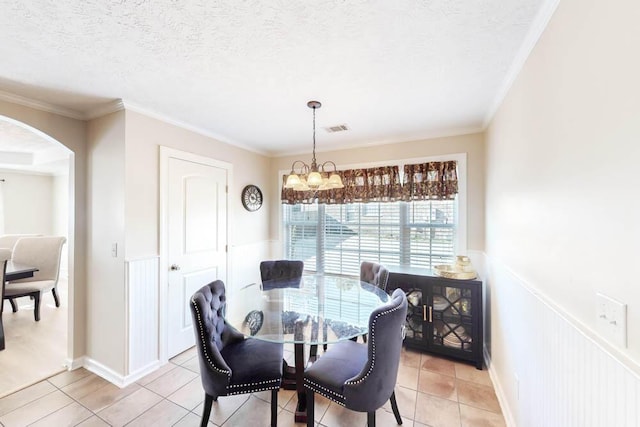 dining room with light tile patterned floors, a textured ceiling, and ornamental molding