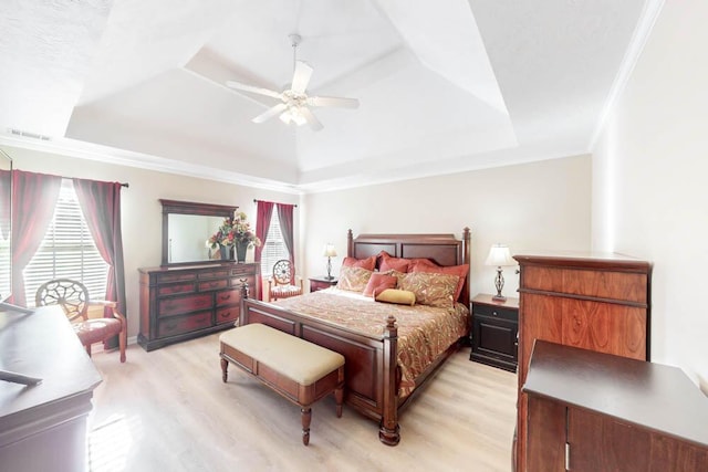 bedroom featuring ceiling fan, light hardwood / wood-style flooring, and a tray ceiling