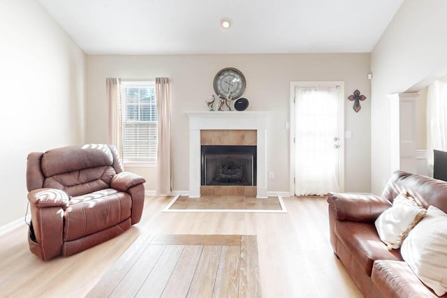 living room with a tile fireplace and light wood-type flooring