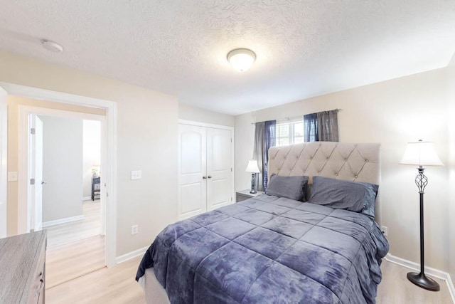 bedroom featuring light hardwood / wood-style floors, a textured ceiling, and a closet