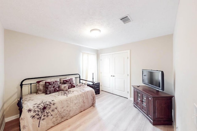 bedroom featuring a closet, a textured ceiling, and light wood-type flooring