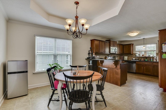 dining space with a notable chandelier, a raised ceiling, ornamental molding, and sink