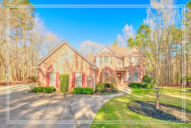 view of front of property with brick siding, driveway, and a front lawn
