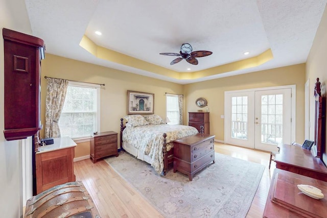 bedroom featuring access to outside, french doors, baseboards, light wood-style floors, and a raised ceiling