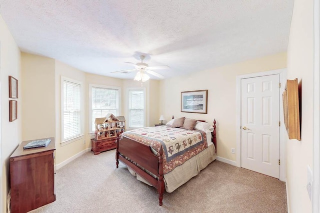 bedroom with baseboards, light colored carpet, ceiling fan, and a textured ceiling