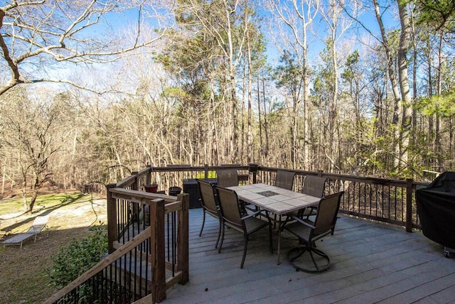 wooden deck with outdoor dining area and a view of trees