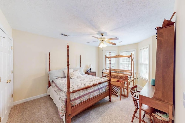 bedroom featuring baseboards, visible vents, ceiling fan, a textured ceiling, and light colored carpet