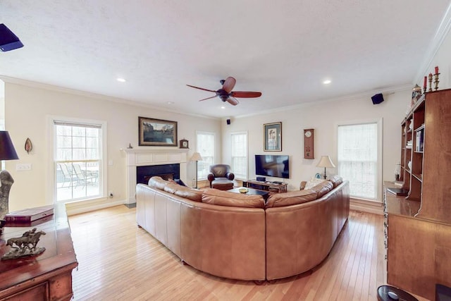 living room with light wood-type flooring, ornamental molding, a ceiling fan, recessed lighting, and a fireplace