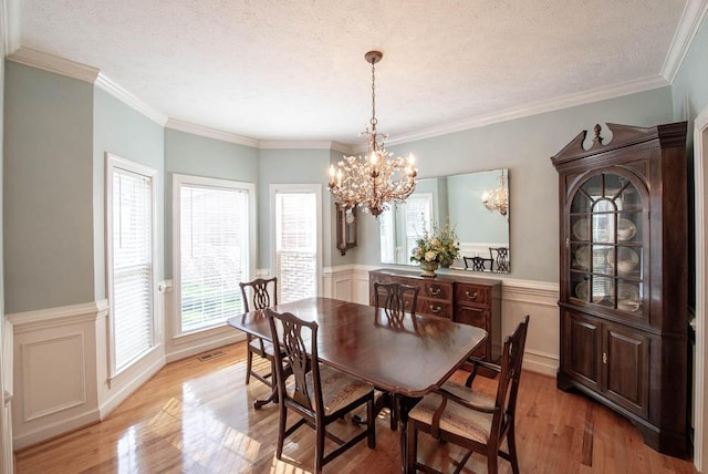 dining space featuring a wainscoted wall, an inviting chandelier, visible vents, and light wood-type flooring