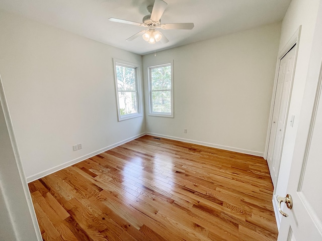 unfurnished bedroom with light wood finished floors, a closet, a ceiling fan, and baseboards