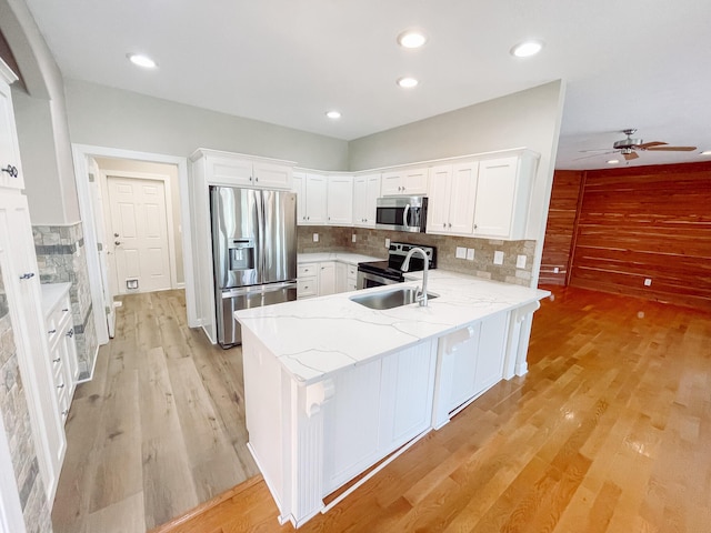 kitchen featuring stainless steel appliances, light wood-type flooring, a peninsula, and white cabinetry