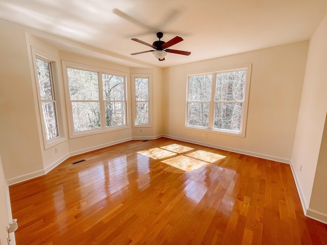 spare room featuring light wood-style floors, visible vents, ceiling fan, and baseboards