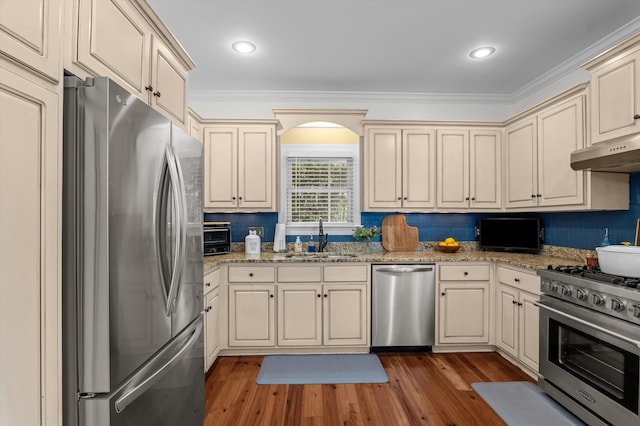 707 Hickman Rd, Augusta, GA 30904 - kitchen featuring appliances with stainless steel finishes, under cabinet range hood, cream cabinets, wood finished floors, and crown molding