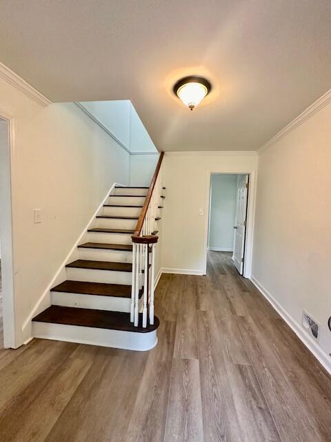 staircase featuring hardwood / wood-style floors and ornamental molding