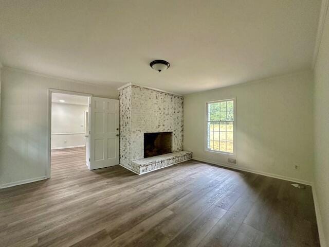 unfurnished living room with hardwood / wood-style flooring, a large fireplace, and crown molding