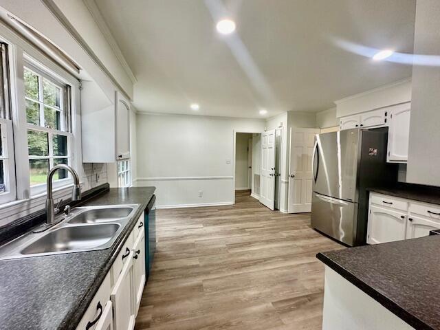 kitchen with stainless steel fridge, tasteful backsplash, sink, light hardwood / wood-style flooring, and white cabinets