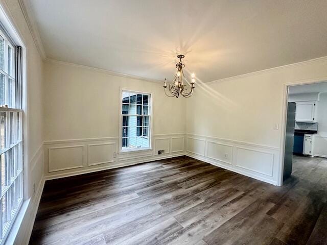 unfurnished dining area with a notable chandelier, crown molding, and dark wood-type flooring