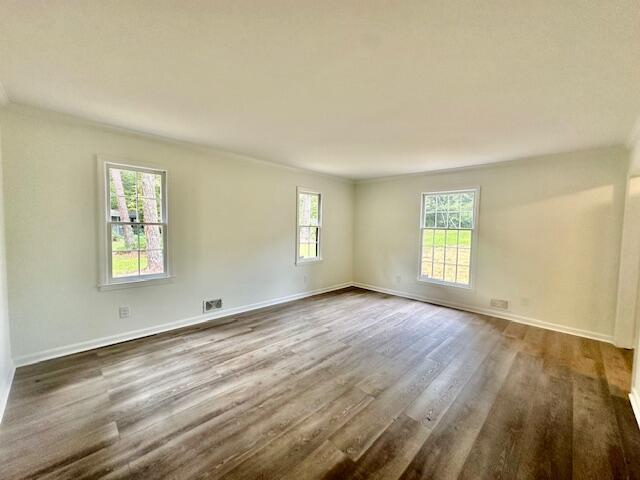 unfurnished room featuring dark hardwood / wood-style flooring, plenty of natural light, and ornamental molding