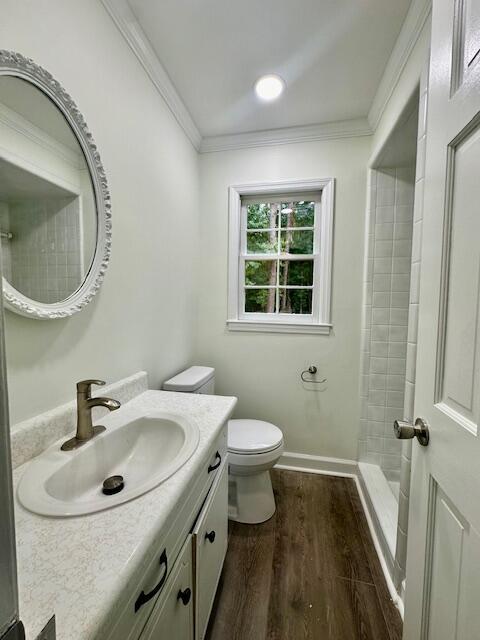 bathroom featuring walk in shower, wood-type flooring, toilet, vanity, and ornamental molding