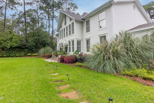 view of property exterior featuring a lawn and a shingled roof
