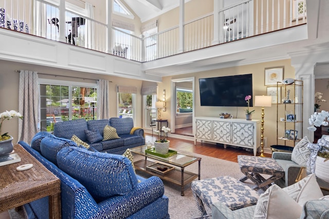 living area featuring ornamental molding, high vaulted ceiling, wood finished floors, and baseboards