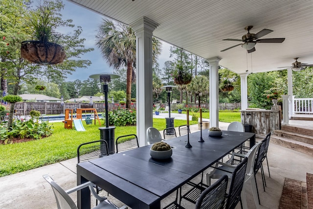 view of patio with a playground, outdoor dining area, ceiling fan, a swimming pool, and a fenced backyard