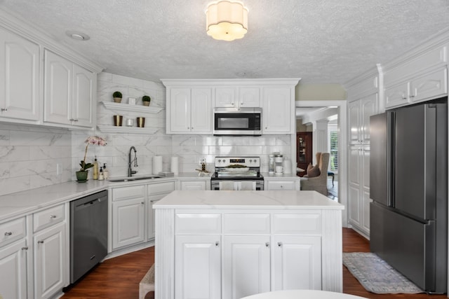 kitchen featuring decorative backsplash, white cabinets, a sink, stainless steel appliances, and light countertops