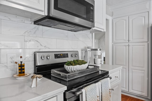 kitchen with light stone countertops, white cabinetry, stainless steel appliances, and tasteful backsplash