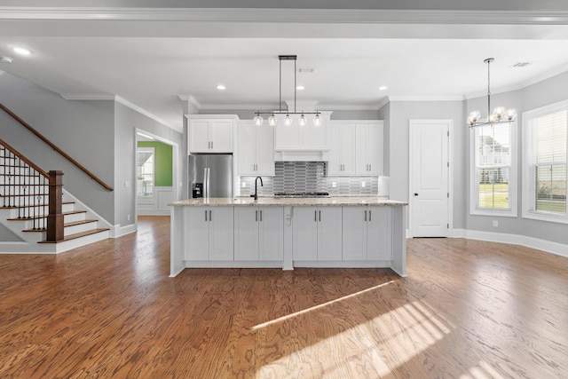 3067 Rosewood Dr, Evans, GA 30809 - kitchen featuring appliances with stainless steel finishes, white cabinetry, wood finished floors, an island with sink, and backsplash