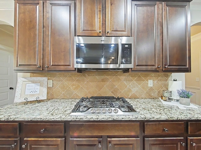 1038 Dietrich Ln, North Augusta, SC 29860 - kitchen featuring appliances with stainless steel finishes, arched walkways, dark brown cabinetry, and decorative backsplash