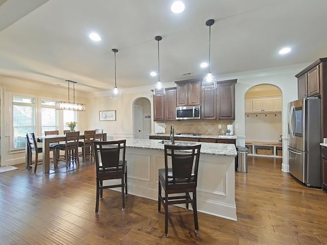 1038 Dietrich Ln, North Augusta, SC 29860 - kitchen with appliances with stainless steel finishes, arched walkways, ornamental molding, light stone countertops, and dark brown cabinets