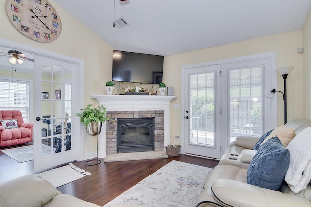 living area featuring a ceiling fan, wood finished floors, plenty of natural light, and a fireplace